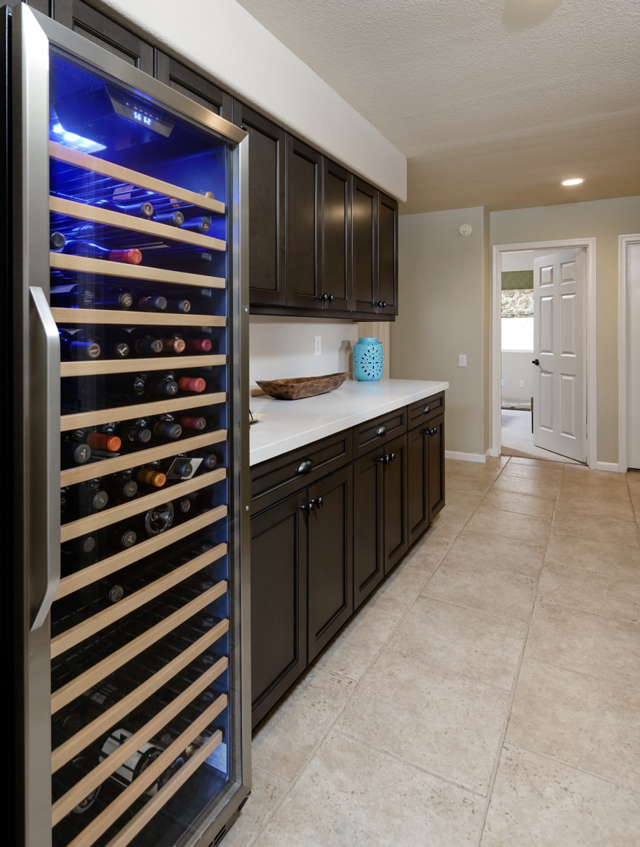 Dark brown upper and lower cabinets with a wine fridge.