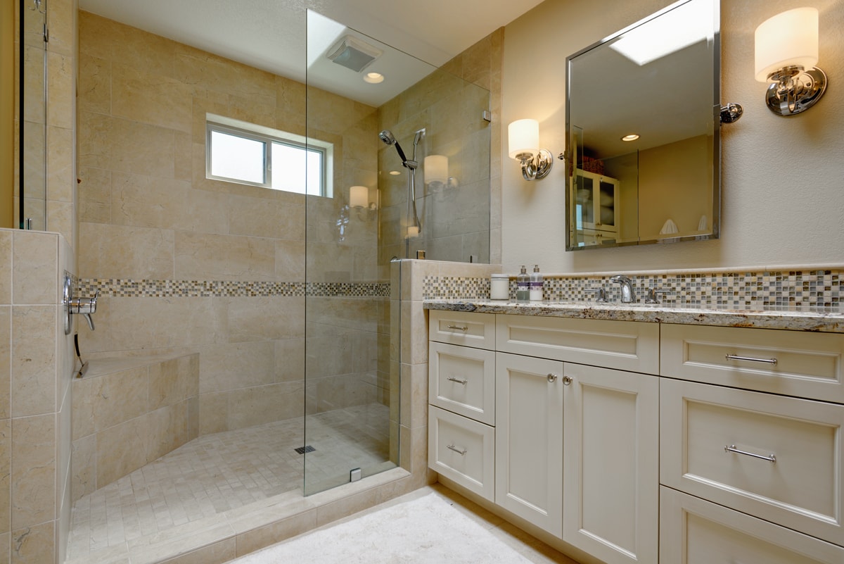 Cream colored shaker-style vanity beside a large glass shower.