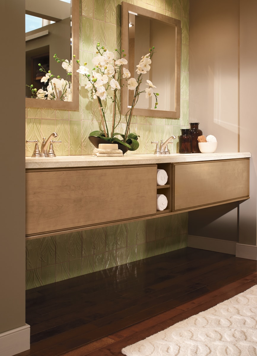 A light colored wood floating vanity with a light green tile backsplash.