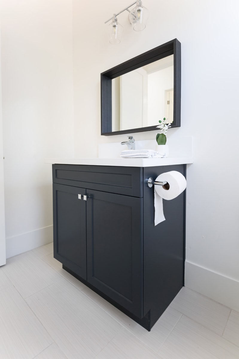 Black bathroom vanity with a black framed mirror in a white bathroom.