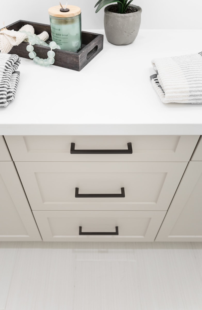 Looking down on a beige vanity with a white countertop and black hardware pulls.