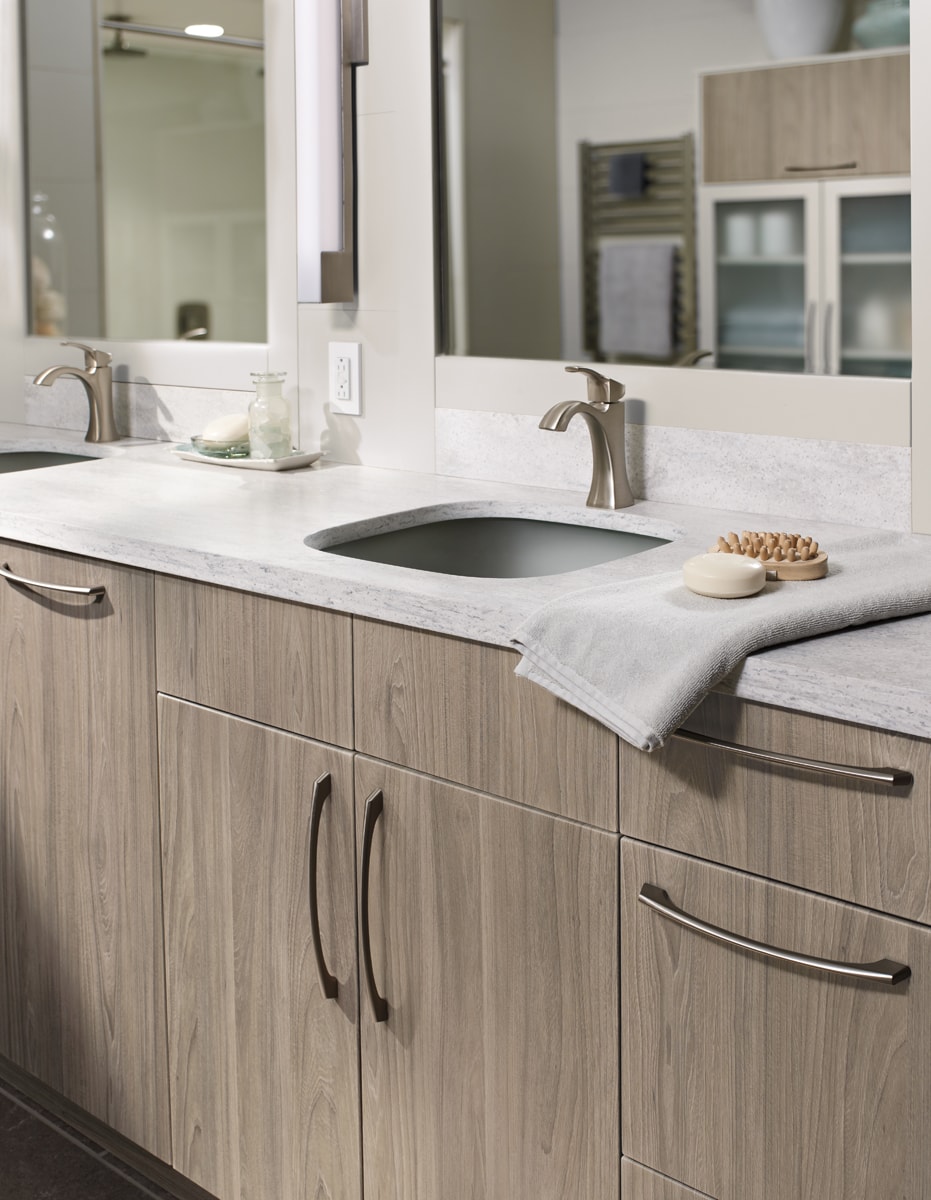 A neutral-colored bathroom vanity with a light grey countertop with a towel on the counter.