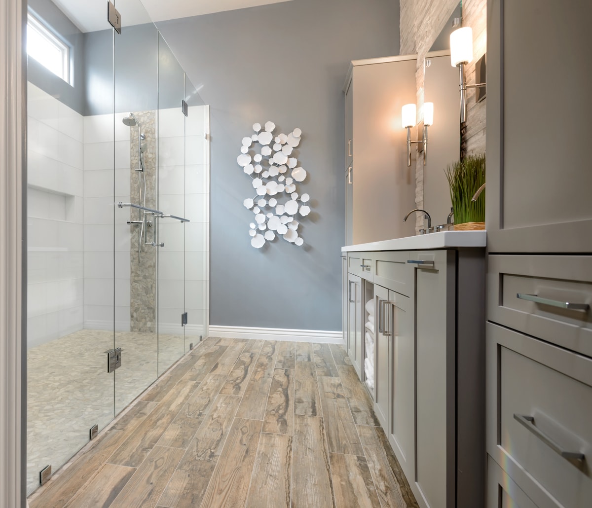 A large glass shower across from a light grey bathroom vanity.