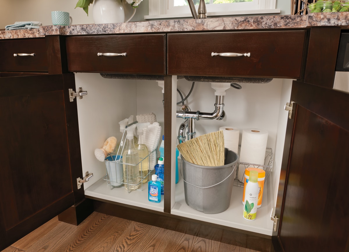 Two open bathroom vanity cabinets that have cleaning supplies underneath the sink.