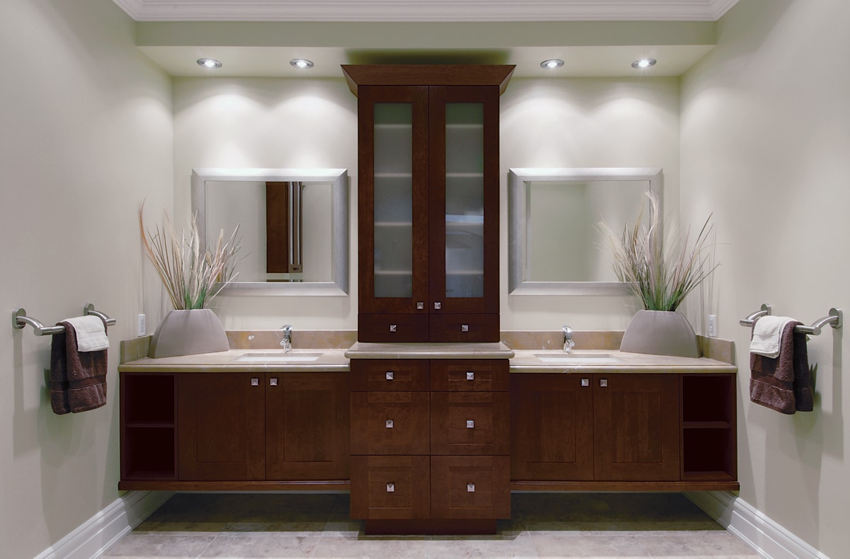 Dark brown double vanity with a column of cabinets in the middle.