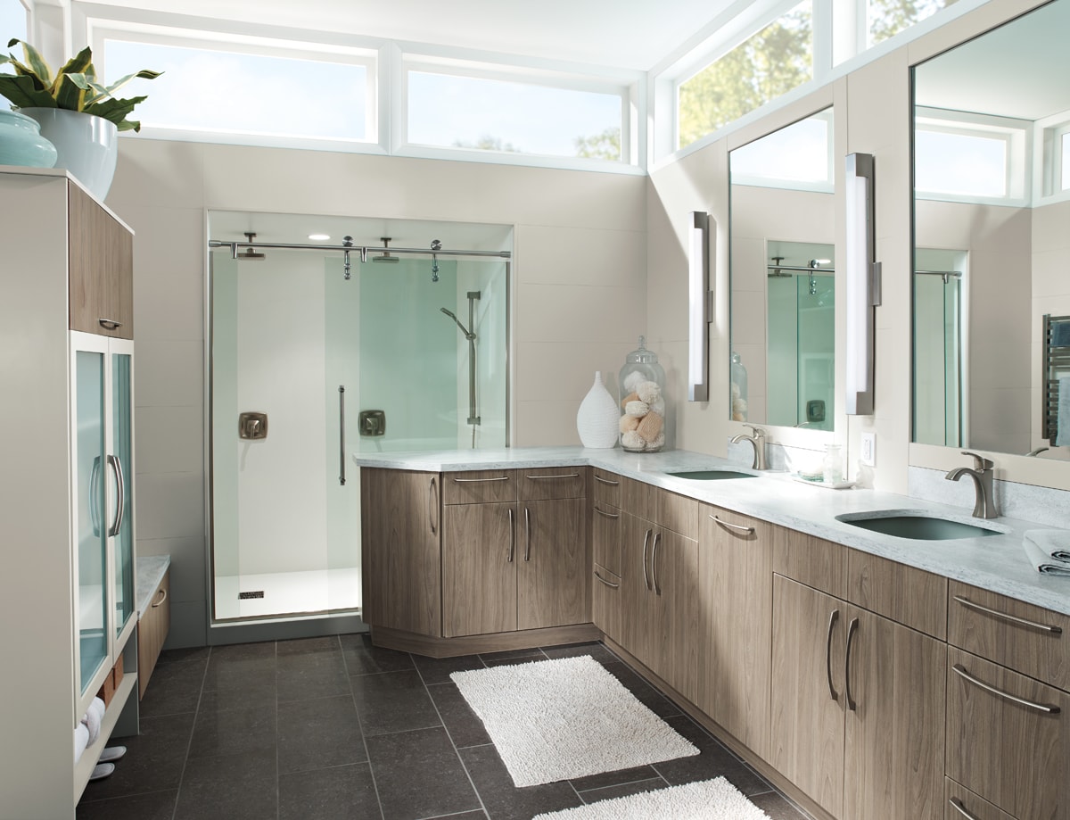 L-shaped bathroom vanity with two sinks in a neutral-toned bathroom with skylights.
