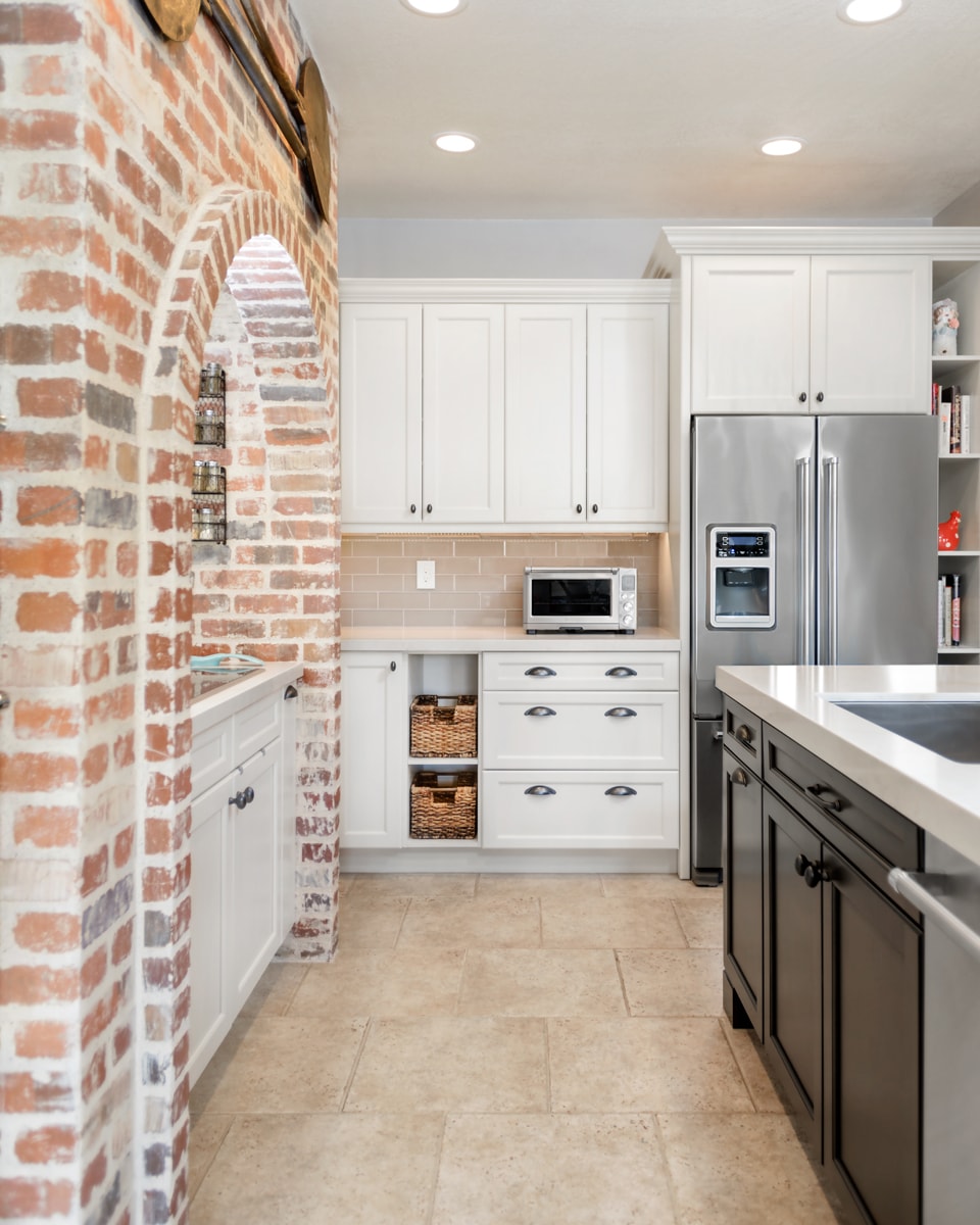 White Shaker style cabinets with a large brick arch in a Transistional style kitchen.