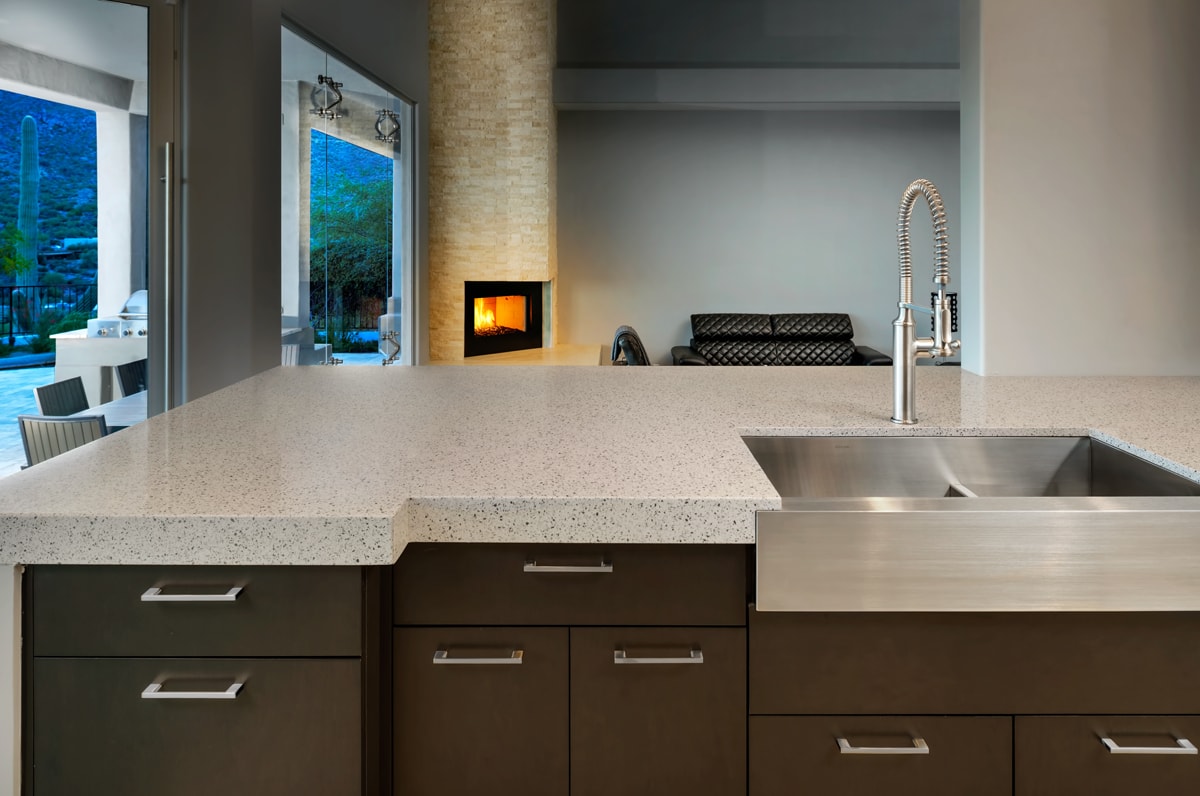 Contemporary kitchen with waterfall countertop and stainless farmhouse style sink.