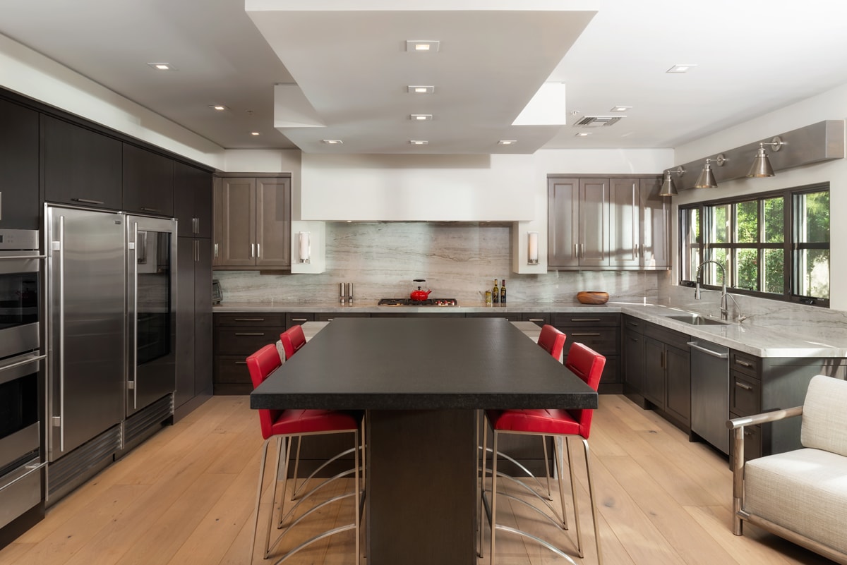 Dark brown modern farmhouse kitchen with large dining table in the center of the kitchen.