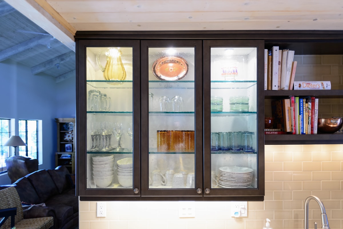 Three glass paneled cabinets displaying glasses and dishware.