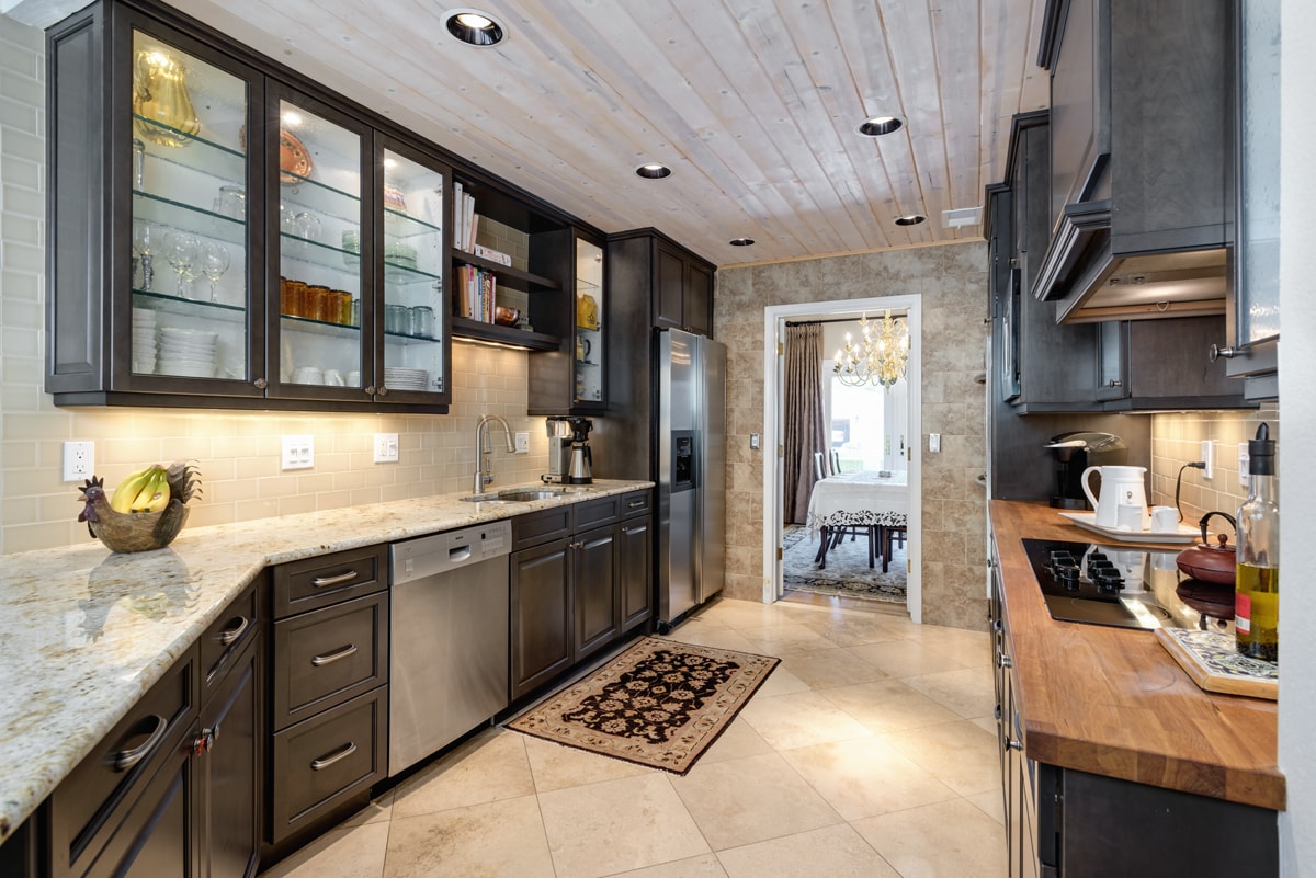 Dark grey kitchen cabinets with light countertops and glass insert upper cabinetry.