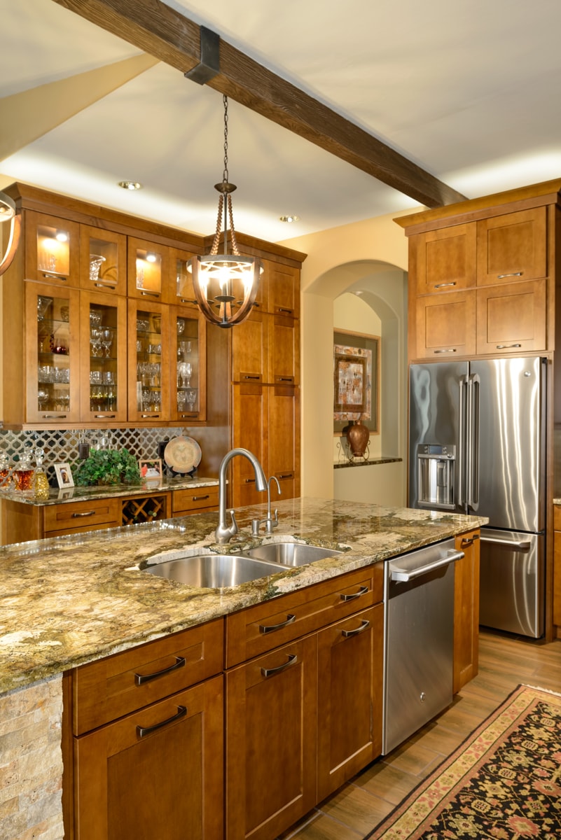 Olde World Design style kitchen with warm woods, granite countertops and stone details.