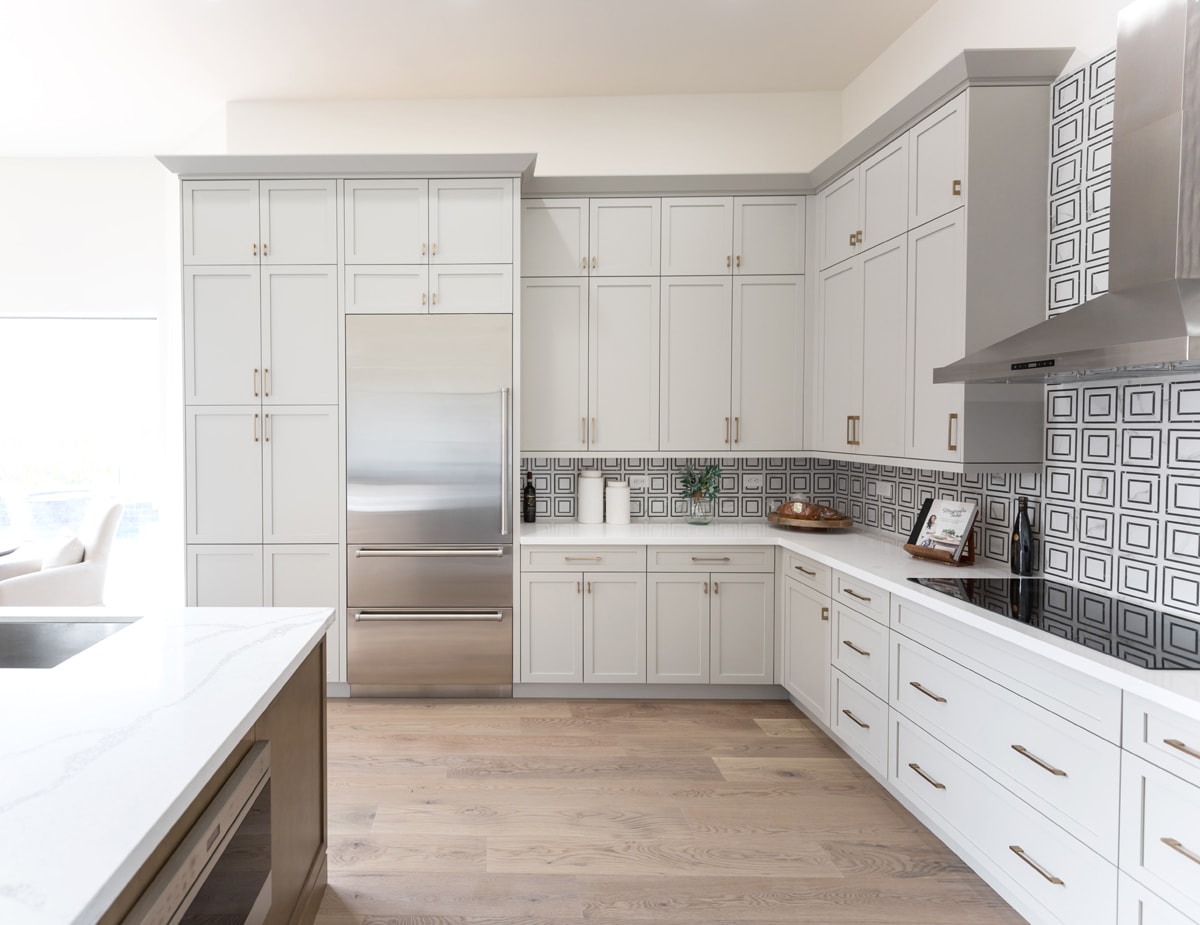 Tall white kitchen cabinetry with light grey crown moulding.