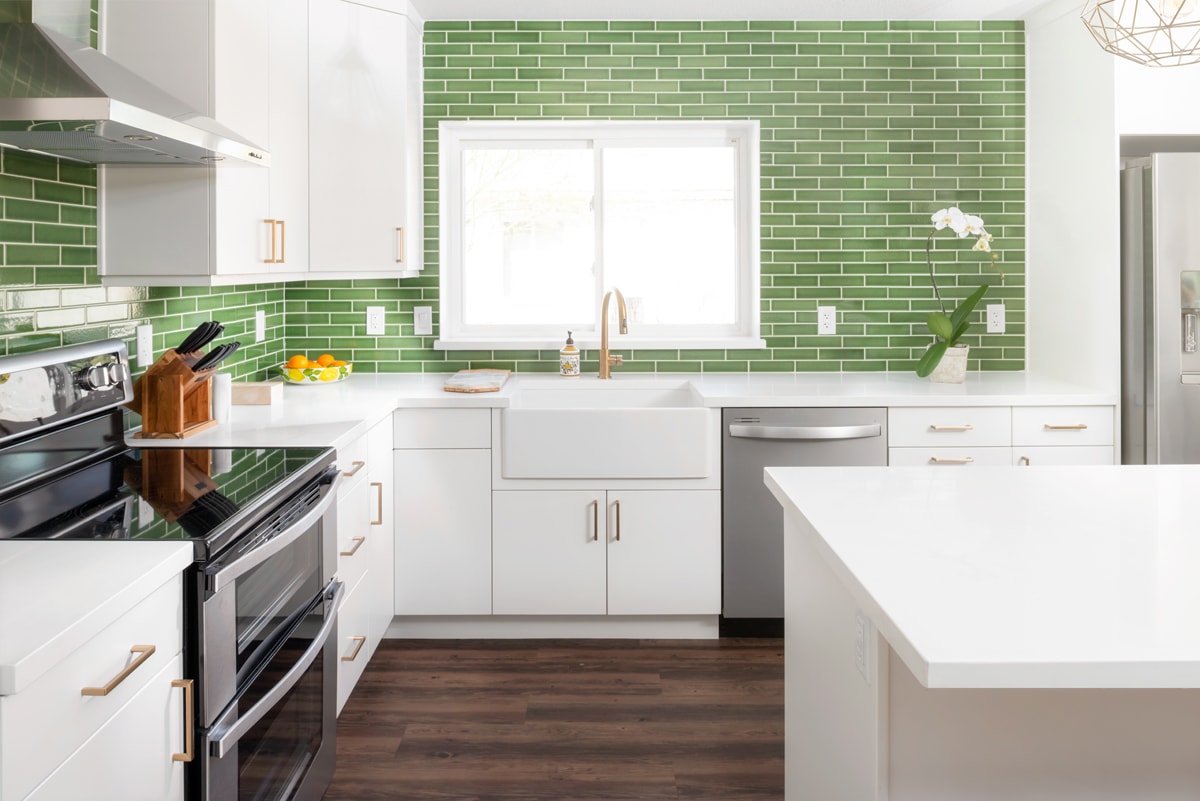 White kitchen cabinets with a vibrant green tile backsplash.