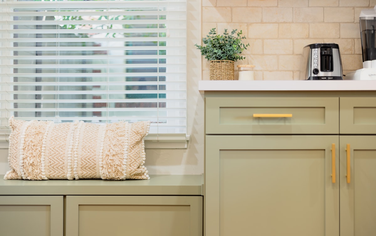 Green bench seating beside green cabinets with white countertops.
