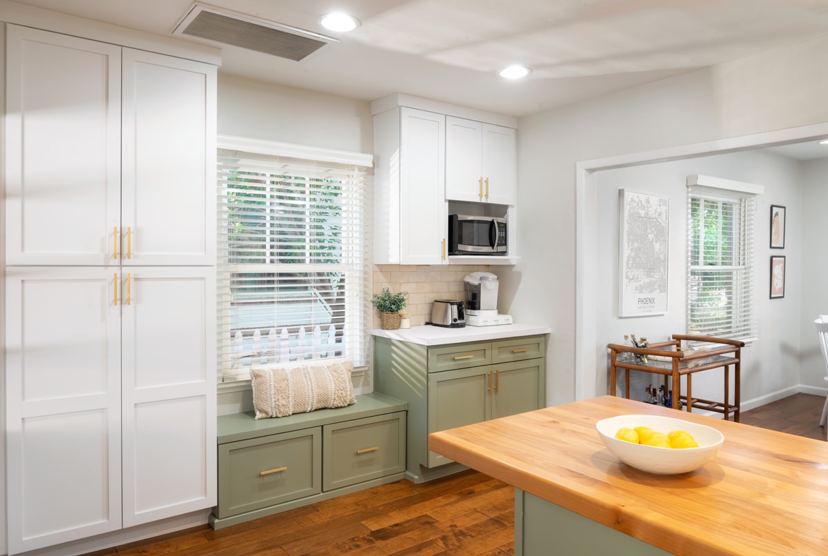 Tall white cabinets beside green bench seating and a coffee nook.