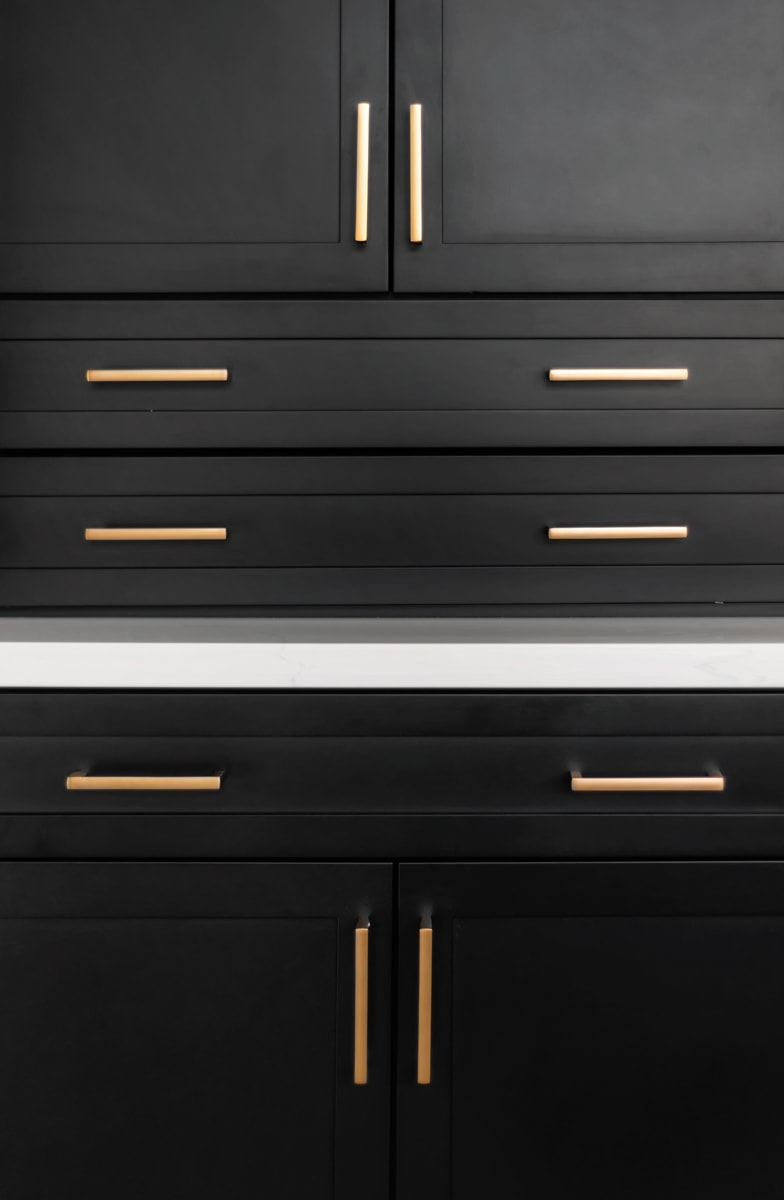 Several black shaker style cabinets with gold hardware pulls.