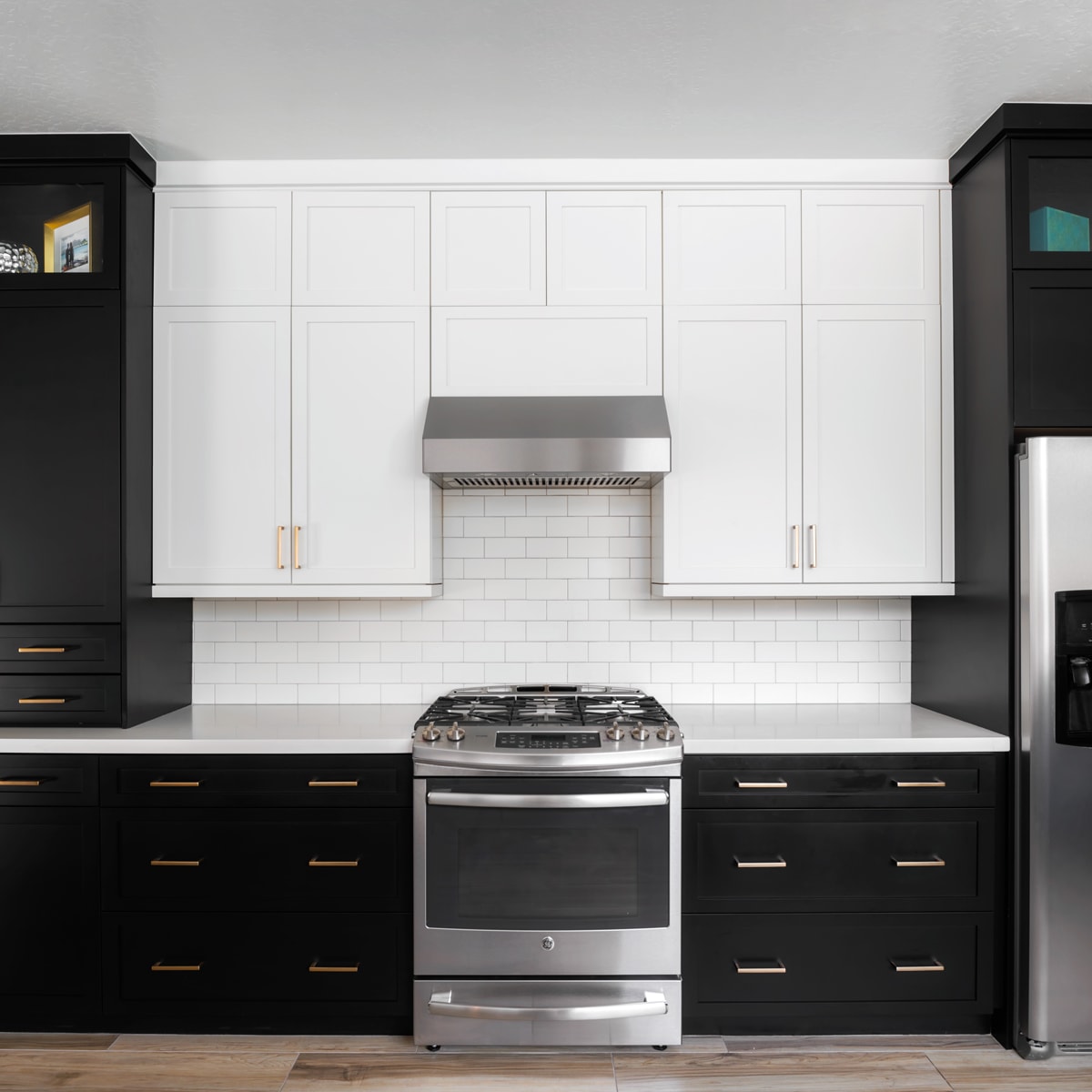 Tall white shaker cabinets and lower black shaker cabinets with a stove in the middle.