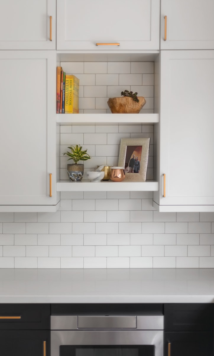 White shaker style cabinets with two floating shelves placed between two cabinets.