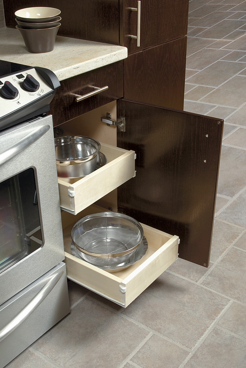 An open dark brown cabinet door with two roll-out shelves containing pots and pans.
