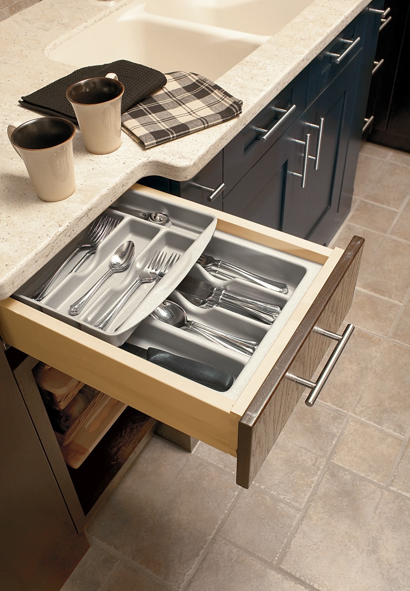 An open kitchen drawer with two layers of utensil tray inserts.