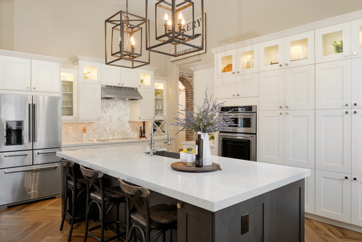 A large kitchen with tall white cabinetry and a dark brown kitchen island with bar seating in the middle.