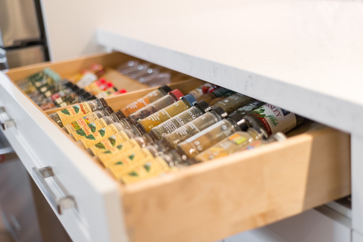 An open drawer with a spice rack full of spices.