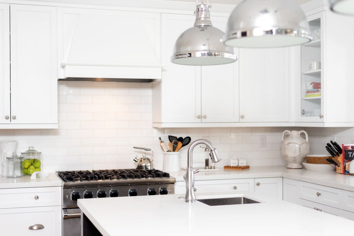 An all-white kitchen with white cabinets, countertops and backsplash.