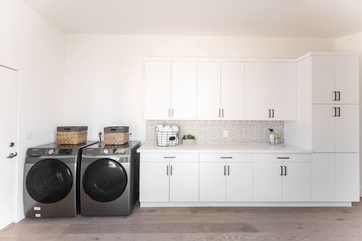 Washer and dryer beside a row of white upper and lower cabinetry.