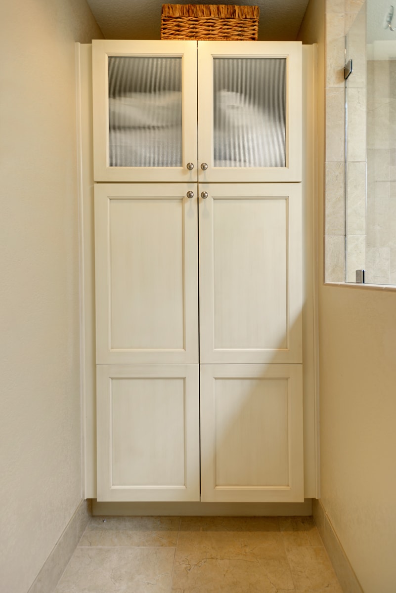 Tall cream cabinet with a mixture of glass and solid doors.